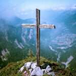 cross on top of a mountain with a village below