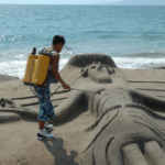 A man creating a sand sculpture of a crucifix on the beach